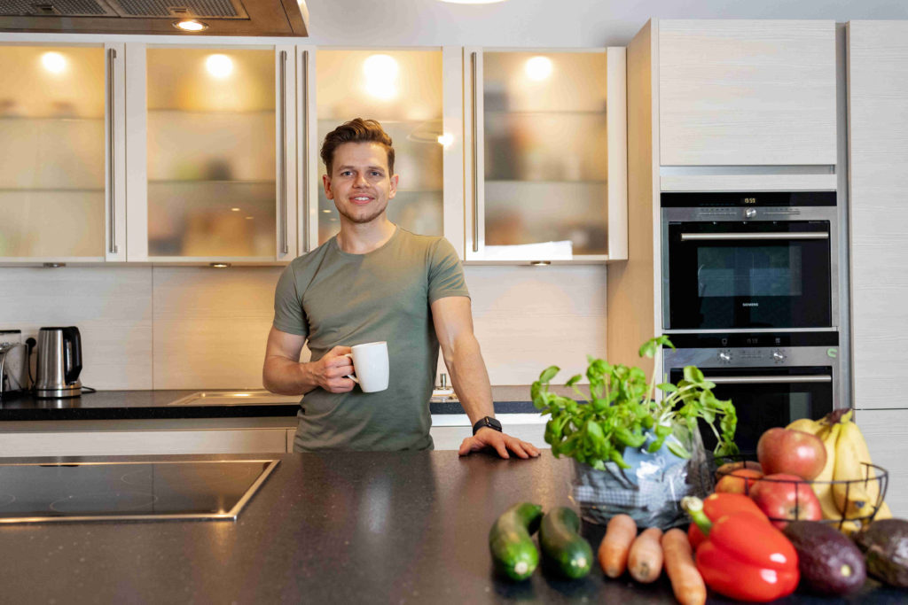 Ein Portrait von Michael Henning in einer Küche mit einer Kaffeetasse in der Hand